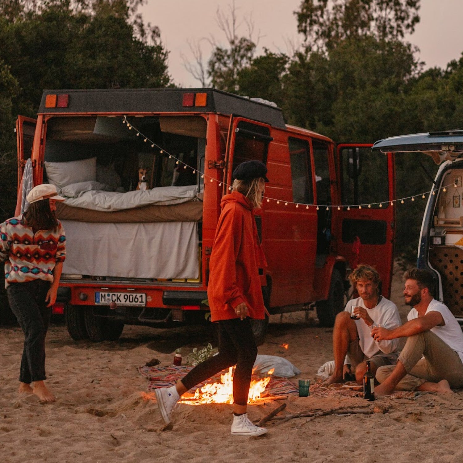 Sascha und Angie sitzen mit ihren Freunden Phil und Lui am Lagerfeuer, mit ihren Vans.