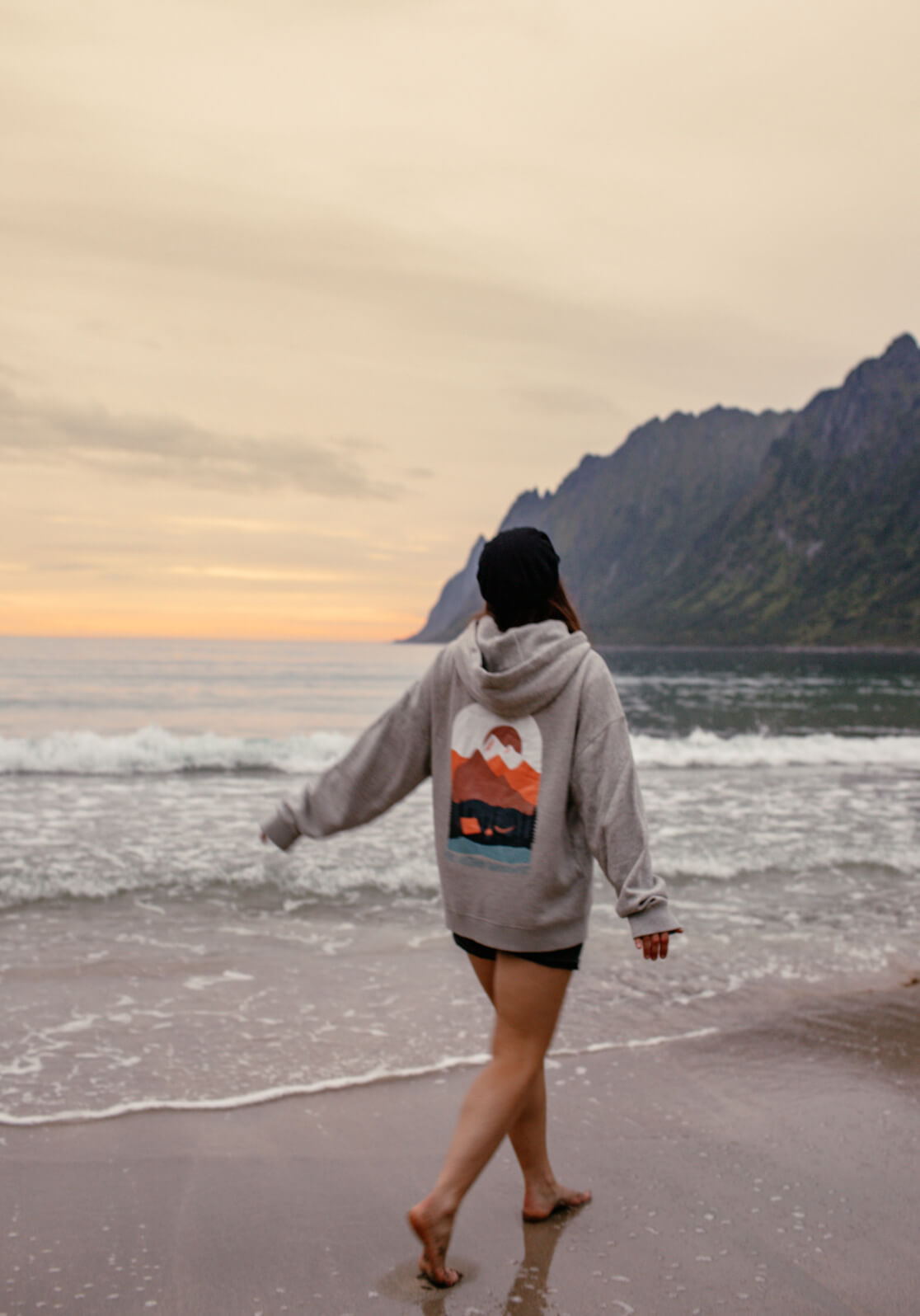 Angie trägt den upgecycelten Hoodie, der in Zusammenarbeit mit Phil und Lui entstanden ist, am Meer.