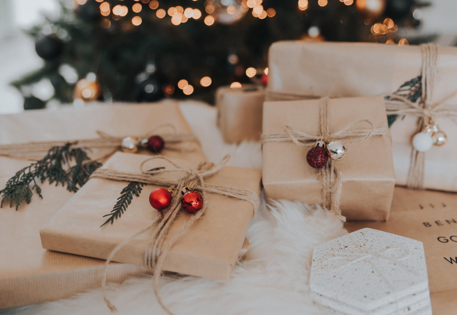 Liebevoll verpackte Geschenke in recycelten Geschenkpapier, mit Kugeln und Tannenästen als Deko. 