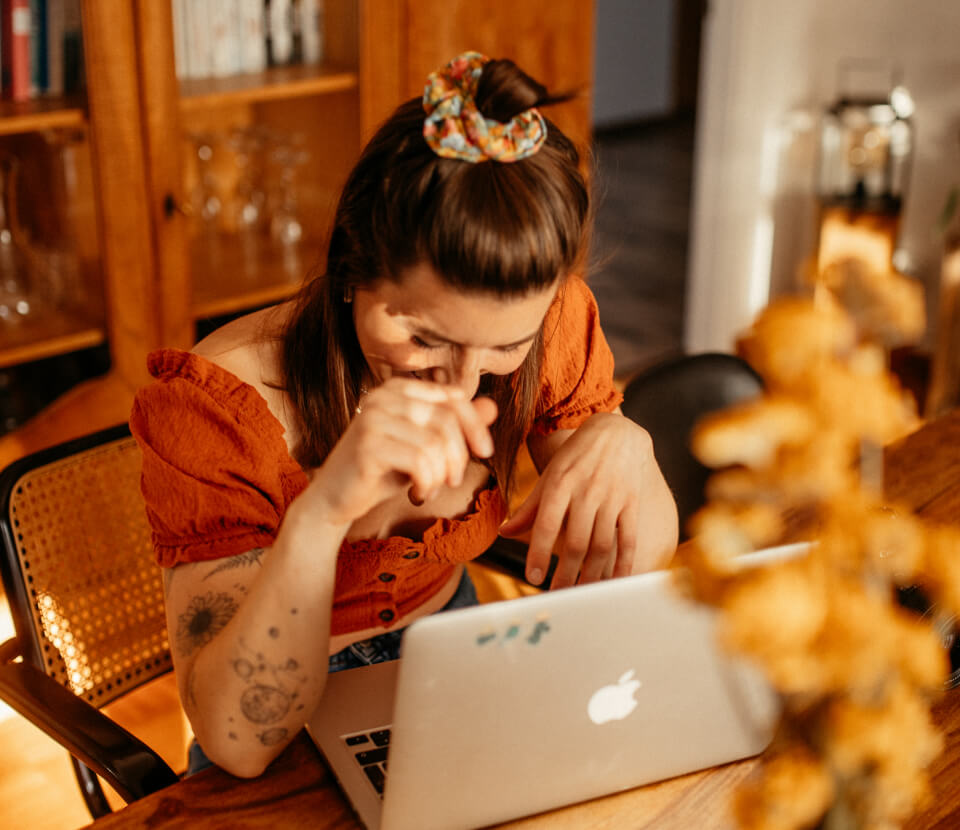 Angie sitzt im Wohnzimmer am Laptop und arbeitet. 